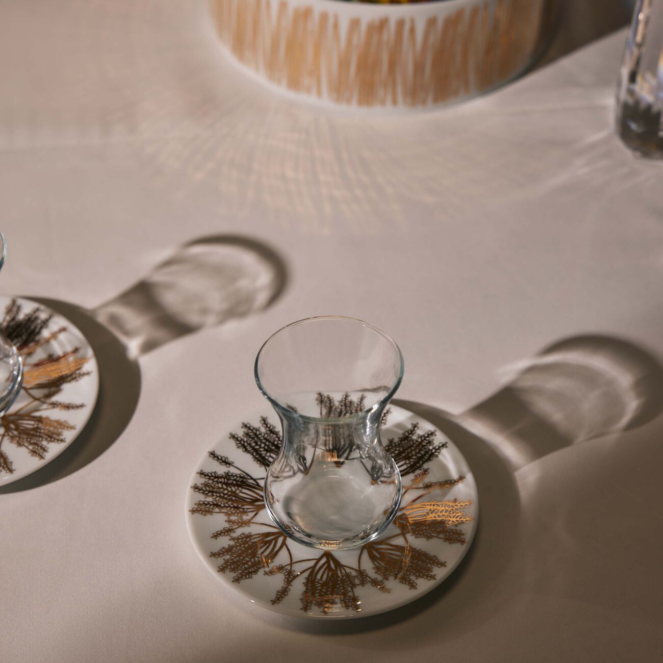 طقم تمرة بالتعاون مع رزان العزوني برانش المؤلف من فنجانين عربيين للشاي مع صحنيهما باللون الذهبي صلصال طقم تمرة بالتعاون مع رزان العزوني برانش المؤلف من فنجانين عربيين للشاي مع صحنيهما باللون الذهبي